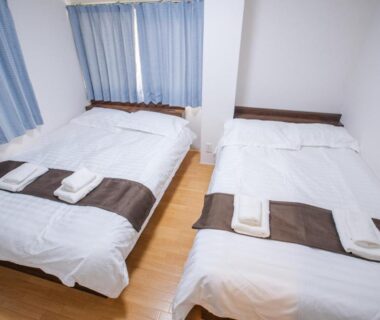 Two beds with white linens and brown runners at Mitomi inn 京急蒲田駅 in Tokyo