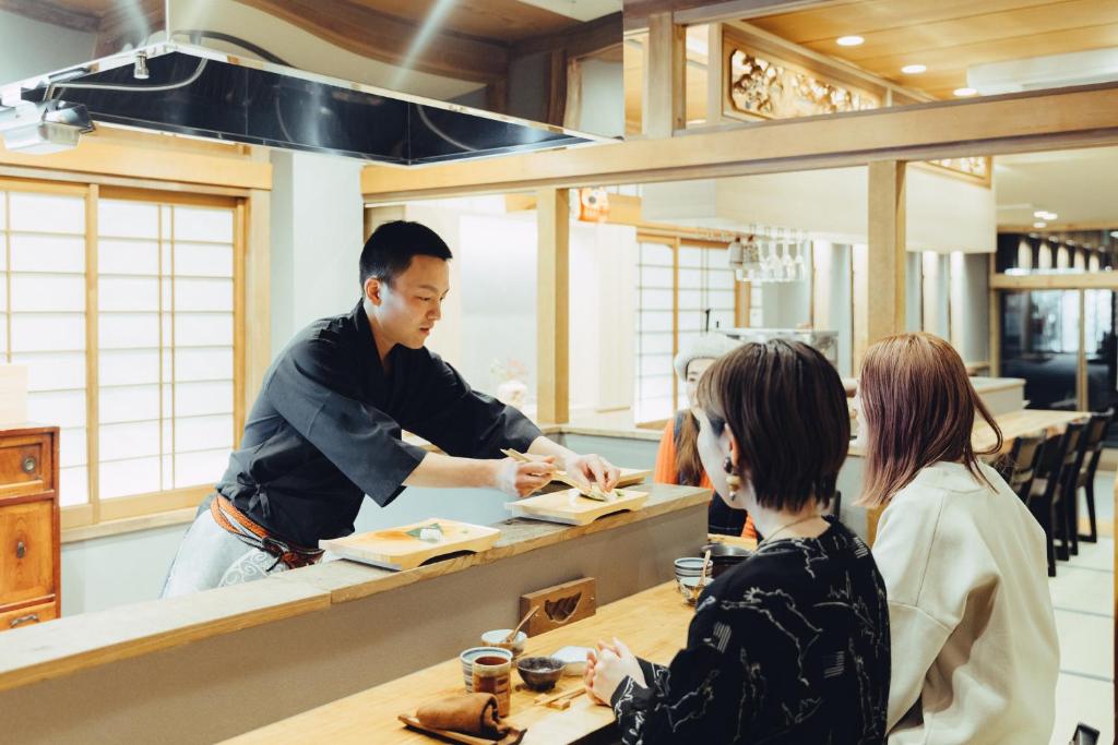 Counter dining at Mitsubikiya Nagano Chef serving guests at wooden counter with shoji screens in Mitsubikiya ryokan, Nagano, Chūbu region, Japan