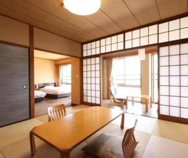 Japanese tatami room with low wooden table, shoji screens and adjoining beds at Miyahama Grand Hotel, Hiroshima