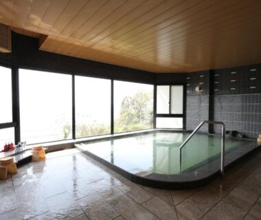 Indoor bath with large windows overlooking greenery at Miyahama Grand Hotel, Hiroshima