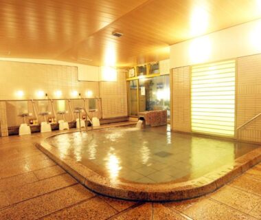 Tiled indoor communal onsen with washing stations and warm lighting at Miyajima Hotel Makoto, Hiroshima