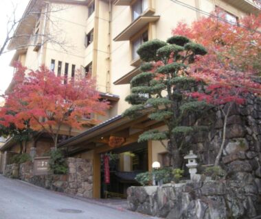 Stone entrance with manicured pine and autumn maples at Miyajima Hotel Makoto in Hiroshima, Chūgoku, Japan