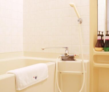 Tiled bath with faucet, handheld shower, folded towel and toiletries at Miyajima Morinoyado in Hiroshima, Chūgoku, Japan