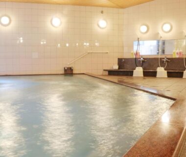 Large tiled indoor onsen pool with wash stations at Miyajima Morinoyado, Chūgoku, Hiroshima, Japan
