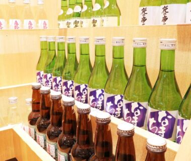 Rows of sake bottles on wooden shelf at Miyajima Morinoyado in Hiroshima