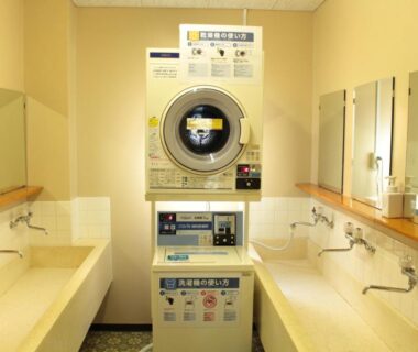 Stacked laundry machines between sinks and mirrors at Miyajima Seaside Hotel, Hiroshima, Chūgoku, Japan