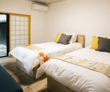 Twin beds with shoji sliding door and small stone courtyard visible at Miyajima Shiro in Chūgoku, Hiroshima