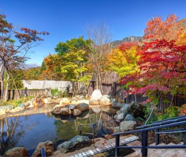 Landscaped rock pond surrounded by autumn maples and a wooden fence at Miyama Ouan in Gifu, Chūbu
