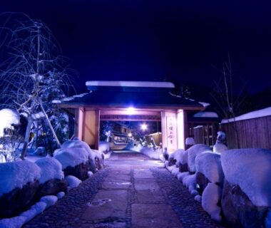 Snow covered stone path leading to illuminated Miyama Ouan entrance in Gifu Chūbu at night