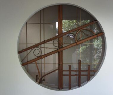 Circular interior window framing wooden railing and shoji screens at Miyoshiya Ryokan Wakayama