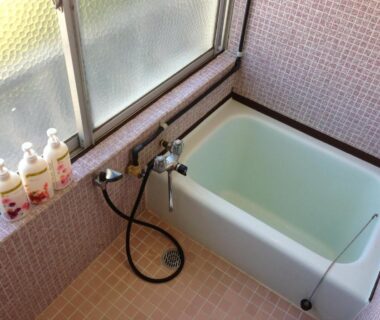 Compact tiled wash area with deep soaking tub, handheld shower and toiletries at Miyoshiya Ryokan in Wakayama