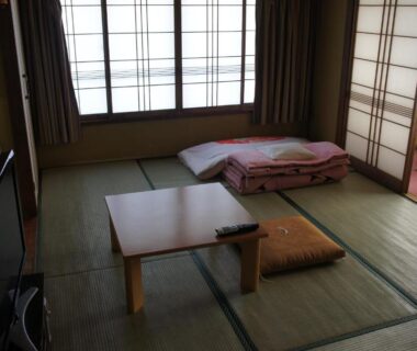 Tatami room with folded futon, low table and shoji screens at Miyoshiya Ryokan in Wakayama, Kansai
