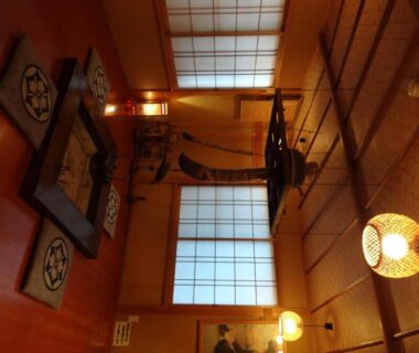 Interior with low wooden table, floor cushions, shoji screens and warm lantern lighting at Mizubasho no Yado Higashi Gunma