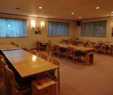 Wooden tables and chairs, warm lit dining room at Mizubasho no Yado Higashi, Gunma, Kantō, Japan