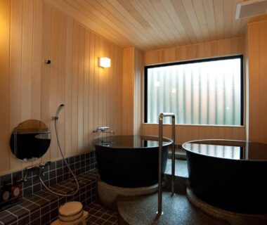 Indoor wooden bathing area with twin round tubs and shower, Mizuhasou, Hiroshima