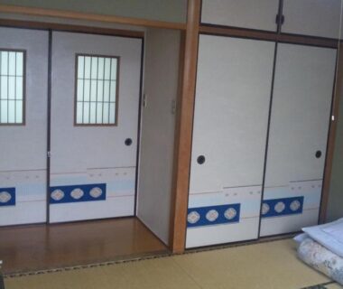 Traditional tatami room with folded futon, sliding fusuma doors and clothes rack at Mizuhokan in Mie