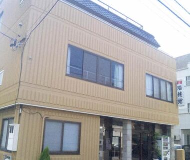 Three story beige ryokan facade with street entrance and windows in Mie, Kansai