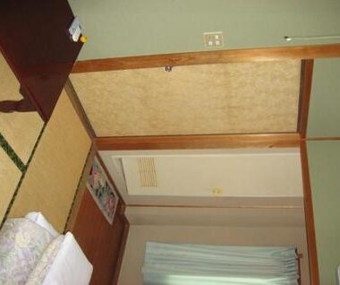 Tatami room with folded futon, shoji sliding door and curtained window at Mizuhokan in Mie