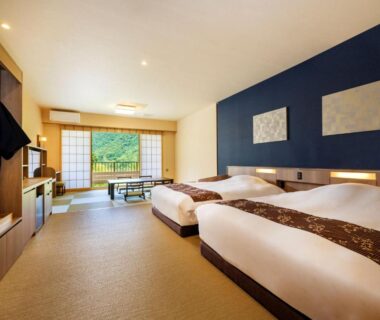 Spacious ryokan guest room with twin beds, tatami seating area and shoji screens at Mizunoto in Kanagawa