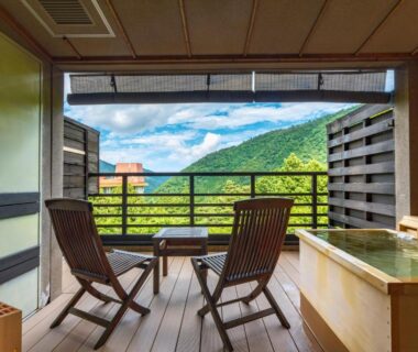 Balcony with wooden soaking tub, two chairs, shoji doors and mountain view at Mizunoto ryokan, Kanagawa