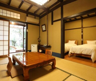 Tatami room with low table and two beds at Momijiya Annex Kyoto