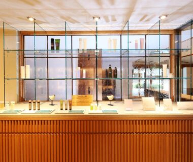 Wooden reception desk with glass display shelves and warm lighting at Monjusou in Kyoto