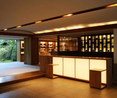 Warm wooden lobby with backlit reception counter and view into a small garden at Monjusou Kyoto