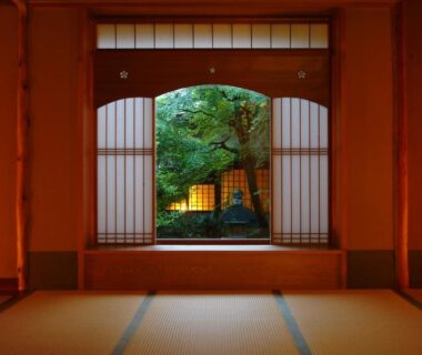 Tatami room facing a framed garden through shoji screens, warm lantern light at Monjusou Shourotei Kyoto