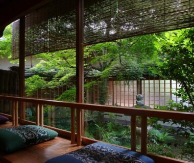 Wooden engawa with cushions and bamboo blinds overlooking a lush enclosed Japanese garden at Monjusou Shourotei Kyoto