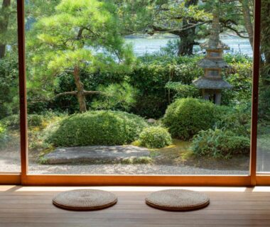 Wooden engawa with two round cushions overlooking manicured garden and stone lantern at Monjusou Shourotei Kyoto Kansai