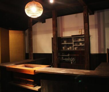 Warm-lit wooden counter and shelves with ceramics in a traditional ryokan interior at Monzen Okagero, Nara, Kansai
