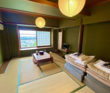 Tatami room with folded futon, low table, shoji window and paper lanterns at Monzen Okagero in Nara
