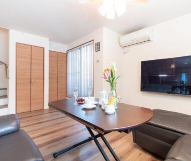 Compact living area with sofas, low table and wall-mounted TV at Mori House In 西日暮里I, Tokyo