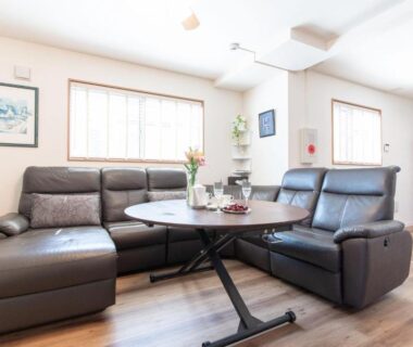 Bright lounge with leather sofas, round table and glass-front cabinet Mori House In 西日暮里I Tokyo