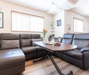 Bright communal lounge with leather sofas, low wooden table and large windows at Mori House In 西日暮里I Tokyo