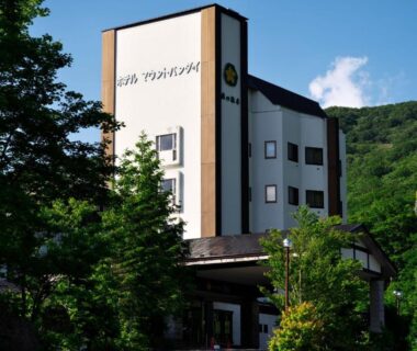 Exterior view of Mori no RyoTei Mount Bandai framed by green trees with mountain backdrop in Fukushima, Tōhoku