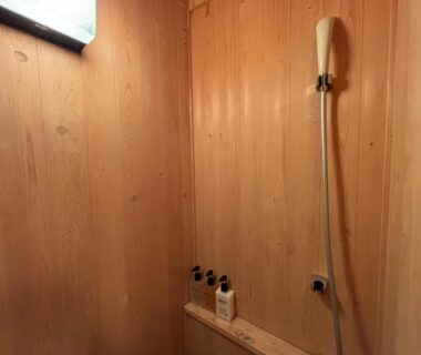 Handheld shower and amenity bottles in wooden stall at Mori no yu Kira No Sato, Shizuoka