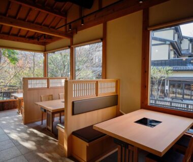 Sunlit wooden dining booths with tables and large windows at Mori no yu Kira No Sato, Shizuoka