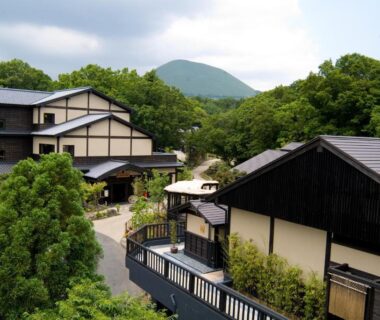 Wooden ryokan buildings among trees with mountain backdrop Mori no yu Kira No Sato Shizuoka
