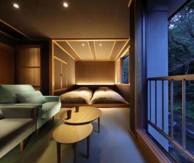 Twin low beds and seating area with sliding screens, balcony overlooking wooded hillside at Moritaya ryokan Fukushima