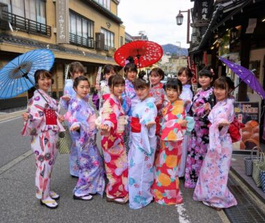 Group wearing colorful kimonos and wagasa umbrellas on traditional street near Morizuya, Hyōgo, Kansai
