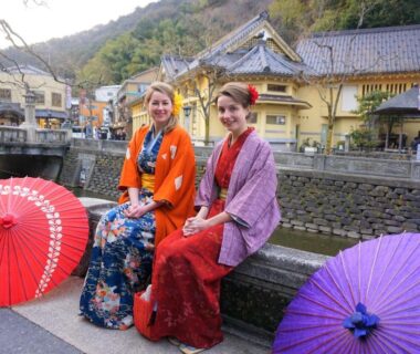 Two women in kimono on riverside with umbrellas near Morizuya in Hyōgo, Kansai
