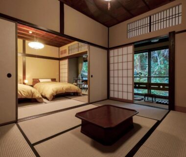Tatami room with low table, shoji screens and adjacent beds at Motoyu Ishiya in Ishikawa, Chūbu