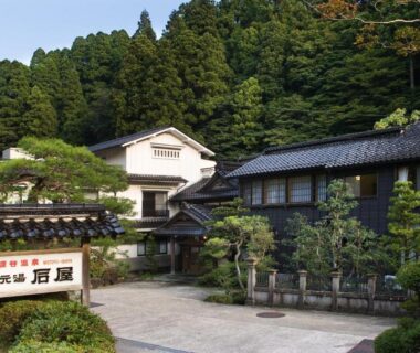 Entrance courtyard of Motoyu Ishiya with traditional wooden buildings, tiled roofs and cedar trees in Ishikawa, Chūbu