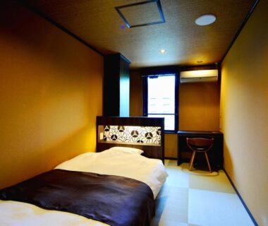 Low twin beds on tatami mat, decorative headboard, desk and window at Mount View Hakone in Kanagawa