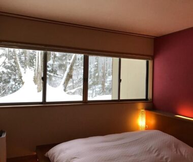 Low bed with warm lamp and snowy window view at Mozumo, Gifu Chūbu Japan