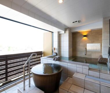 Tiled indoor onsen with wooden soaking tub, glass partition and terrace railing at Mt Fuji Hanayagi no Sho Keizan