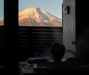 Guest soaking in indoor wooden bath framed by Mount Fuji view at Ryokan Shizuku, Yamanashi