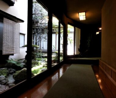 Interior corridor with glass panels beside mossy courtyard garden at Murataya ryokan in Ishikawa, Chūbu