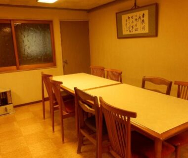Long table with six wooden chairs, framed artwork and window in Murataya dining area, Ishikawa